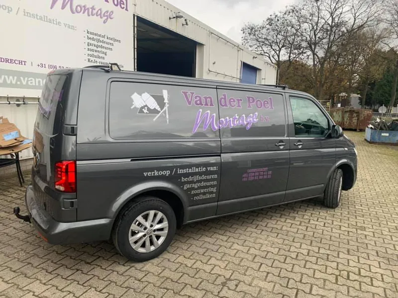 Grijze bedrijfsbus met paarse belettering en diensten op de zijkant