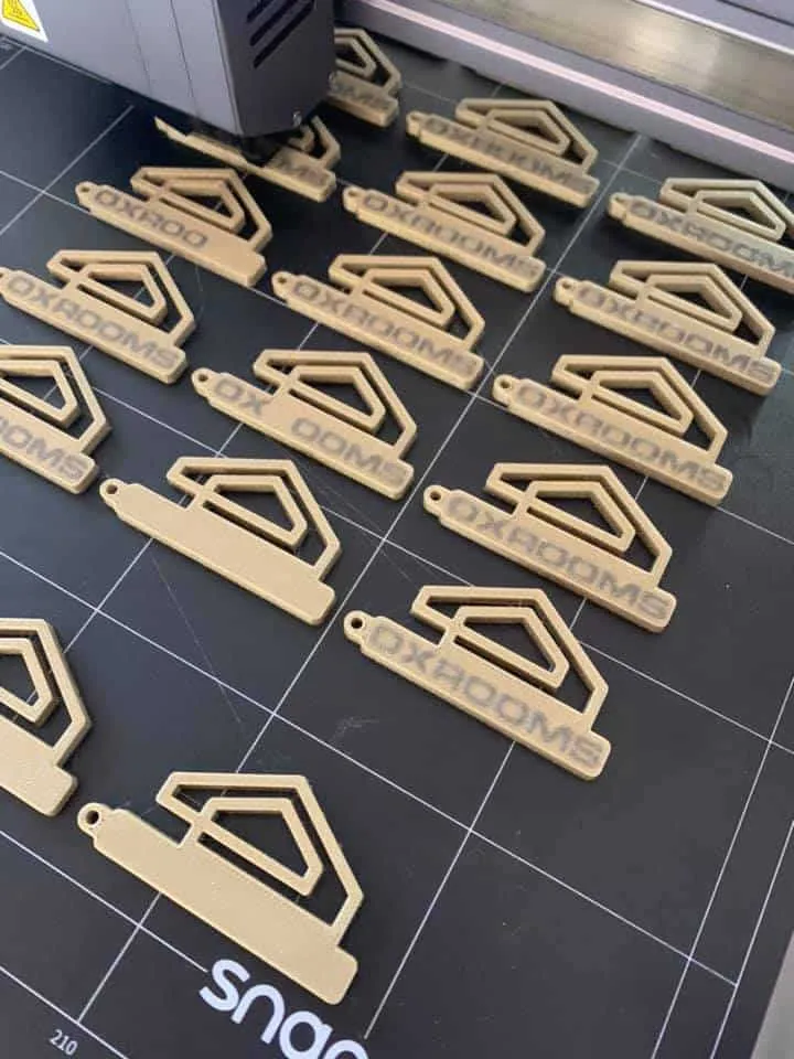 Rijen goudkleurige sleutelhangers met logo op het bed van een 3D-printer