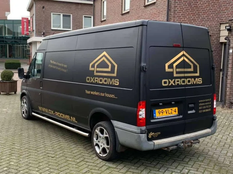 Mat zwarte bestelbus met gouden logo op zijkant en achterdeuren