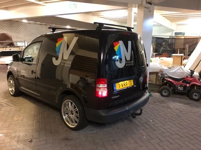 Zwarte bestelauto van achteren met logo op zijkant en achterdeur