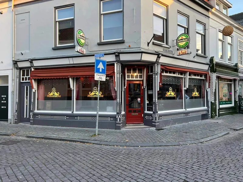 Hoekpand met café waarvan alle ramen goudkleurige logo-stickers hebben