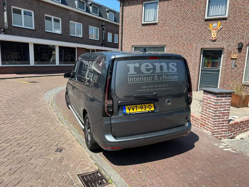 Grijze bestelauto van achteren met grijze belettering en contactgegevens op de achterruiten