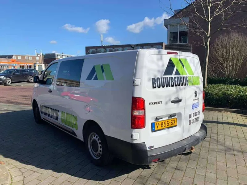 Witte bedrijfsbus schuin van achteren met groen-zwart logo op zijkant en deuren