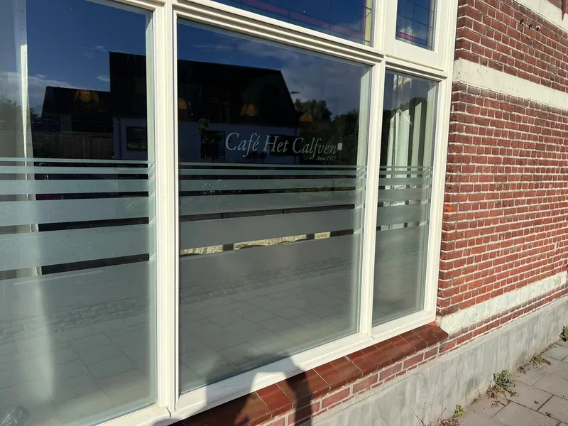 Caféramen met matglasfolie in horizontale banen en sierlijke naam op het glas