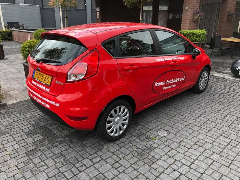 Rode personenauto schuin van achteren met ovaal logo op de portieren