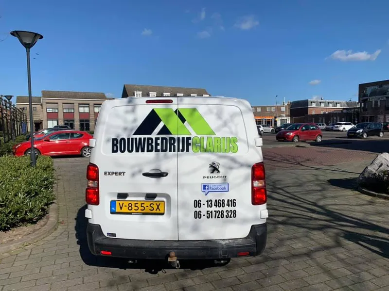Witte bedrijfsbus van achteren met groen-zwart logo en telefoonnummers