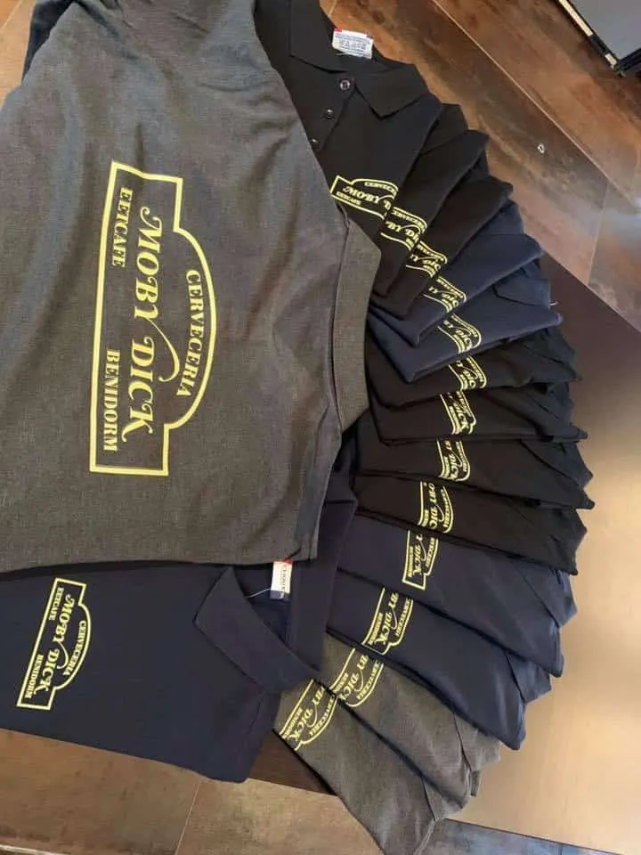 Uitgewaaierde stapel grijze, zwarte en blauwe polo's met geel logo