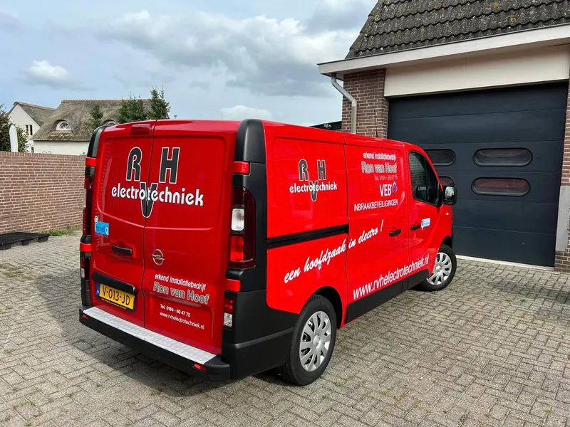 Rode bestelbus schuin van achteren met wit-grijze belettering, logo en slogan