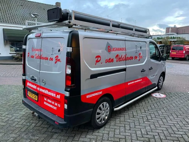 Zilvergrijze bestelbus schuin van achteren met rode belettering op zijkant en achterdeuren