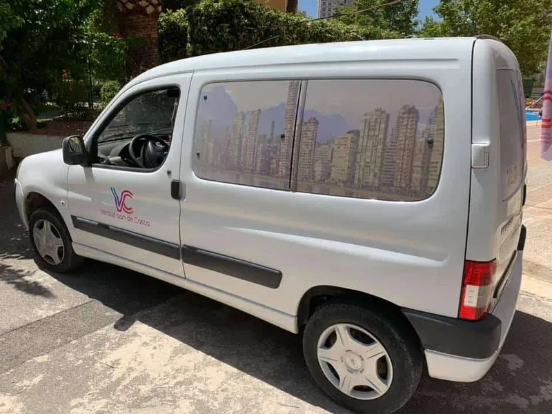 Witte bestelwagen met skyline-print op de zijruiten en logo op het portier