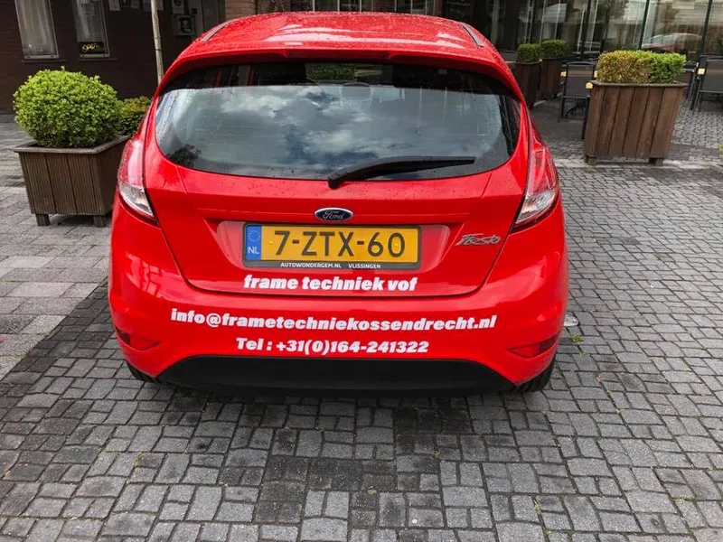 Rode personenauto van achteren met witte belettering onder de achterruit