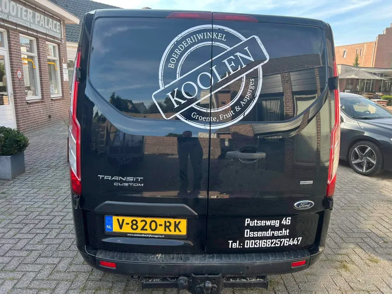 Zwarte bestelbus van achteren met wit stempellogo op de ruiten en adresgegevens