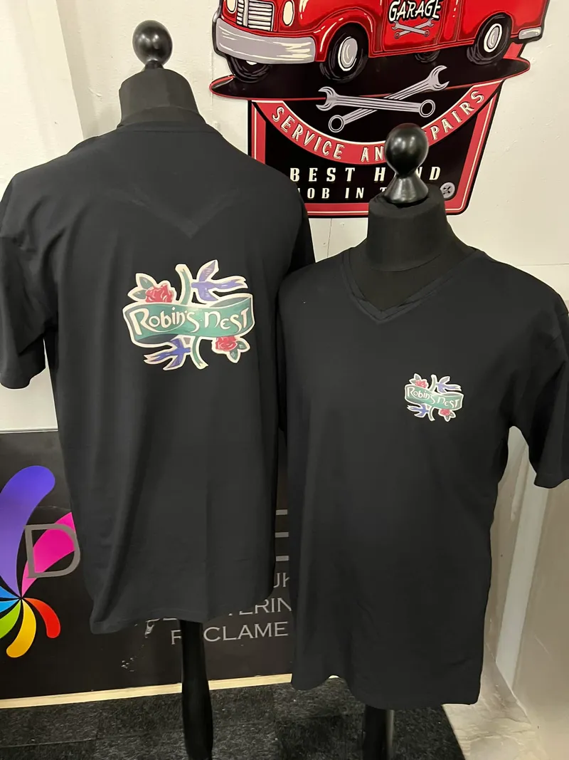 Twee zwarte T-shirts op paspoppen met kleurrijk logo met rozen en zwaluwen