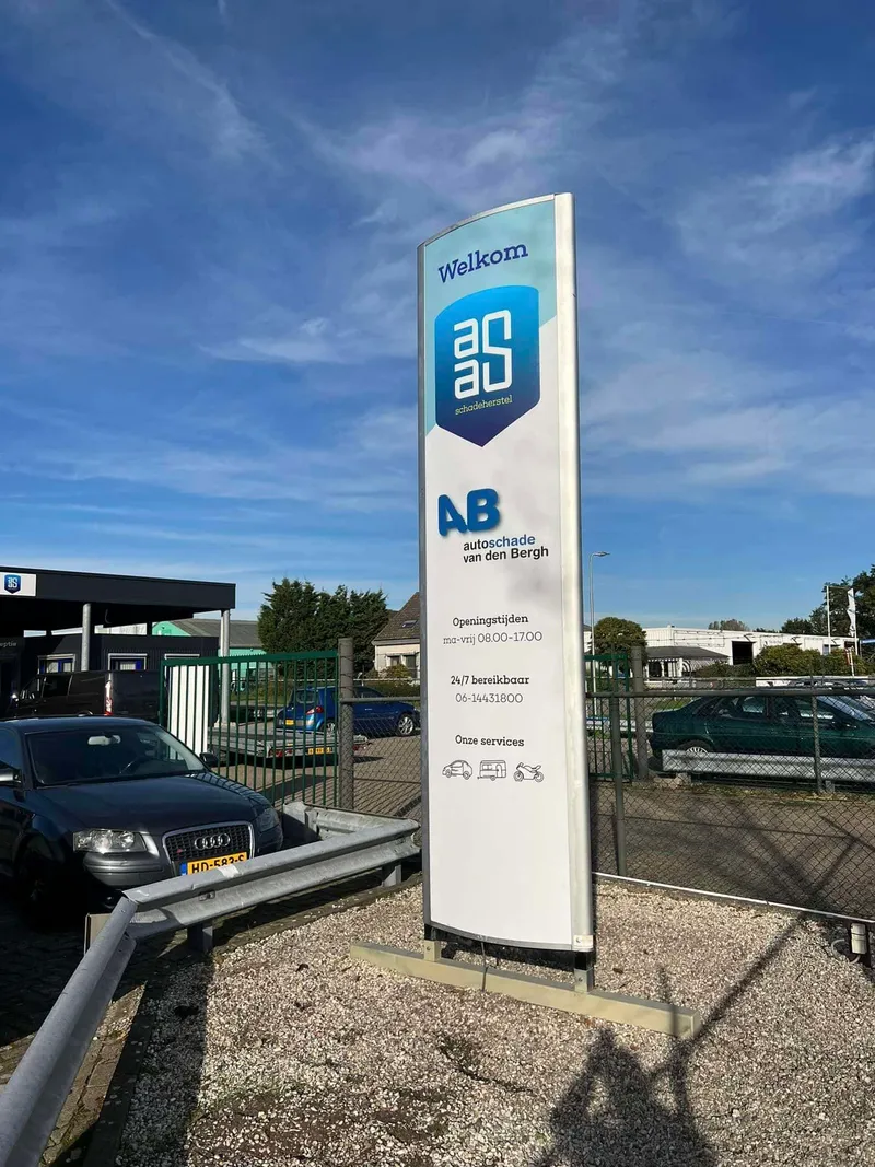 Hoge witte reclamezuil met twee logo's, openingstijden en service-iconen