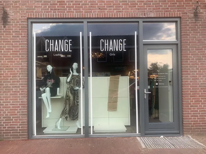 Etalage van kledingwinkel met witte raamletters en belijning op het glas