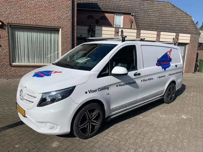 Witte bestelbus schuin van voren met logo op motorkap en zijkant