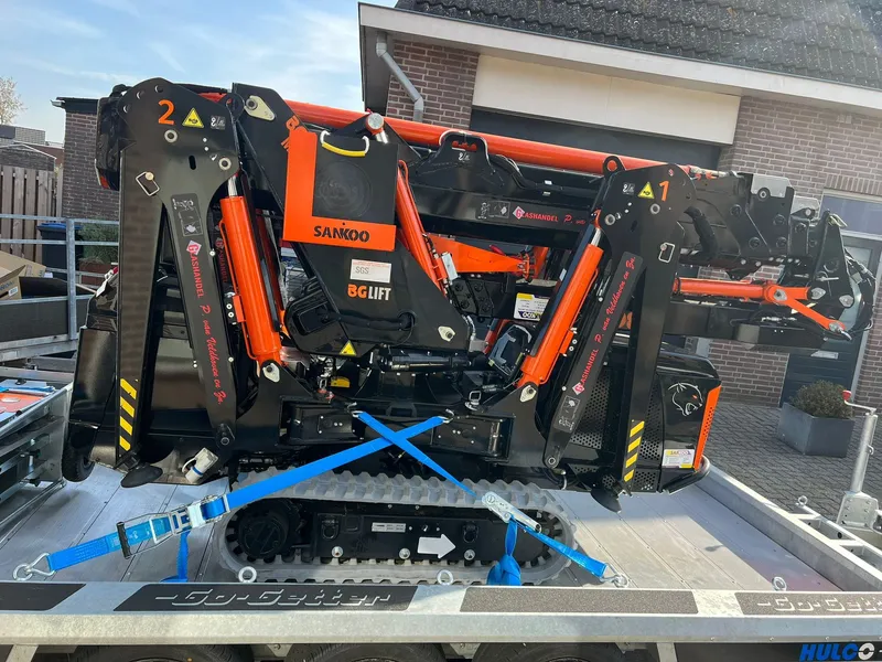Zwart-oranje rupshoogwerker op aanhanger met rode belettering op de stempels