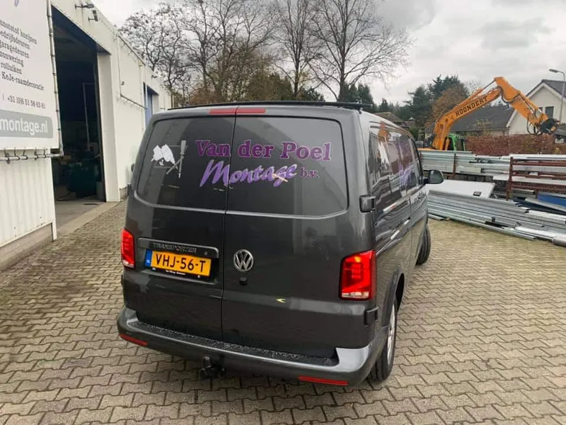 Grijze bedrijfsbus van achteren met paarse belettering op de achterruiten