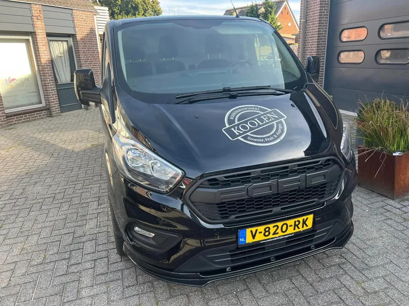 Zwarte bestelbus van voren met wit stempellogo op de motorkap