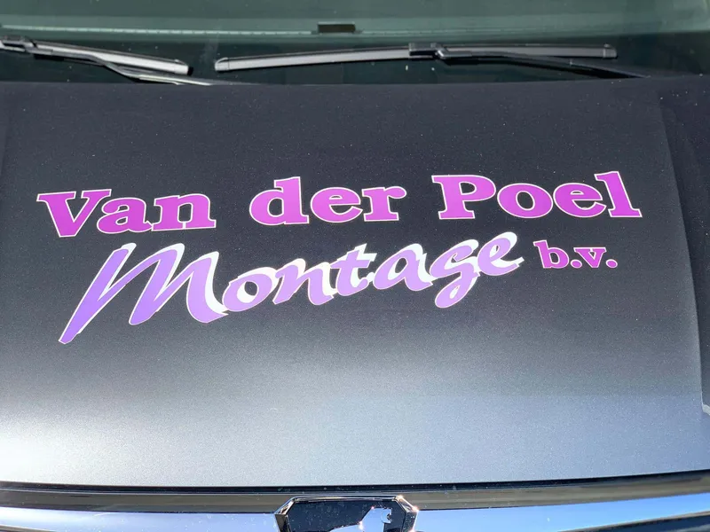 Close-up van motorkap met grote paarse belettering met witte rand