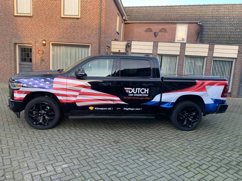 Zwarte pick-up met wrap van landenvlaggen in rood, wit en blauw op de zijkant