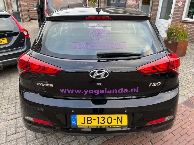 Zwarte hatchback met paarse belettering op achterruit en achterklep voor een pand
