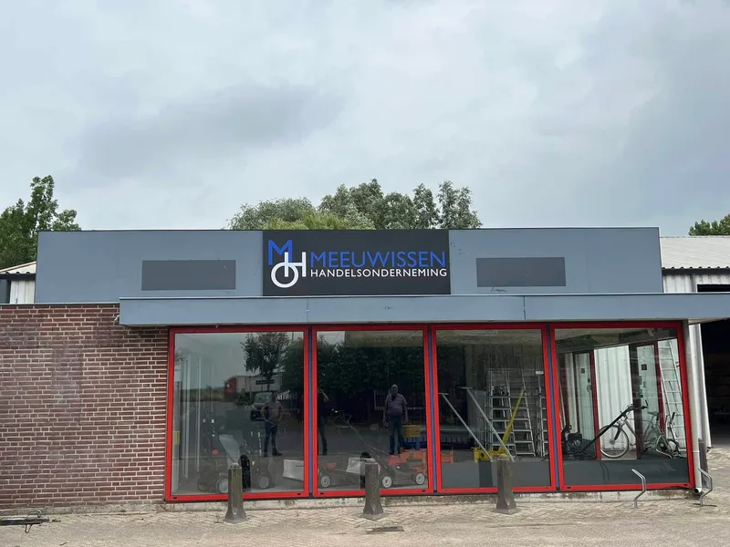 Winkelpand met rode kozijnen en zwart gevelpaneel met logo boven de ramen