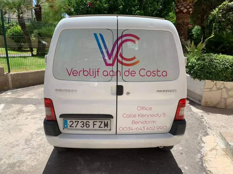 Witte bestelauto van achteren met kleurrijk logo en contactgegevens op de deuren