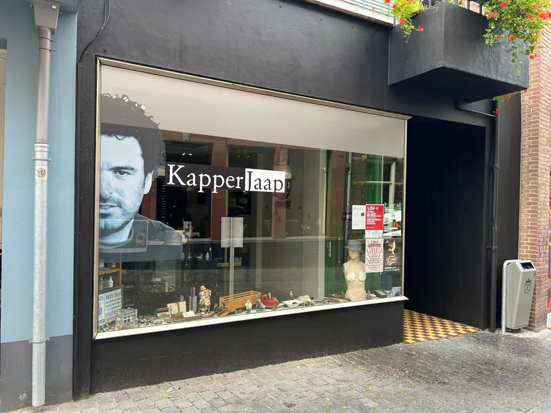Etalage schuin gefotografeerd met raamprint van groot portret en belettering