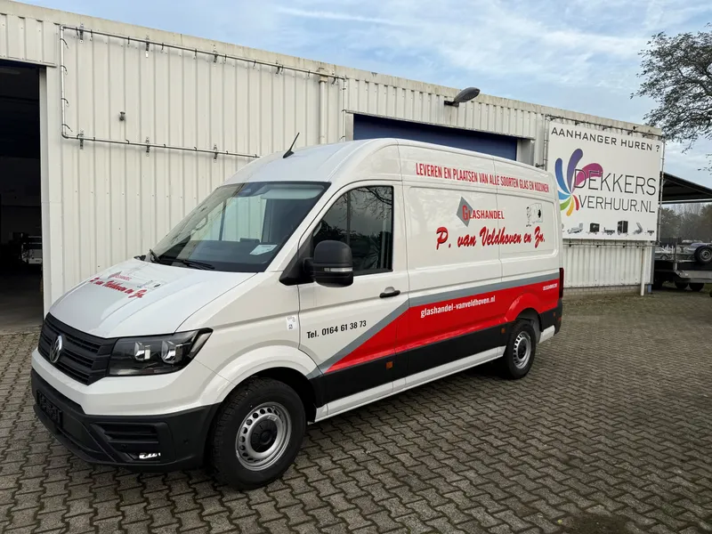 Witte bestelbus met rood-grijze band, logo, slogan en website voor een bedrijfshal