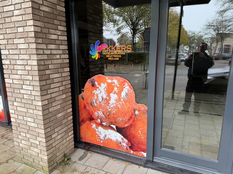 Winkelruit met uitgesneden print van oliebollen en kleurrijk logo op het glas