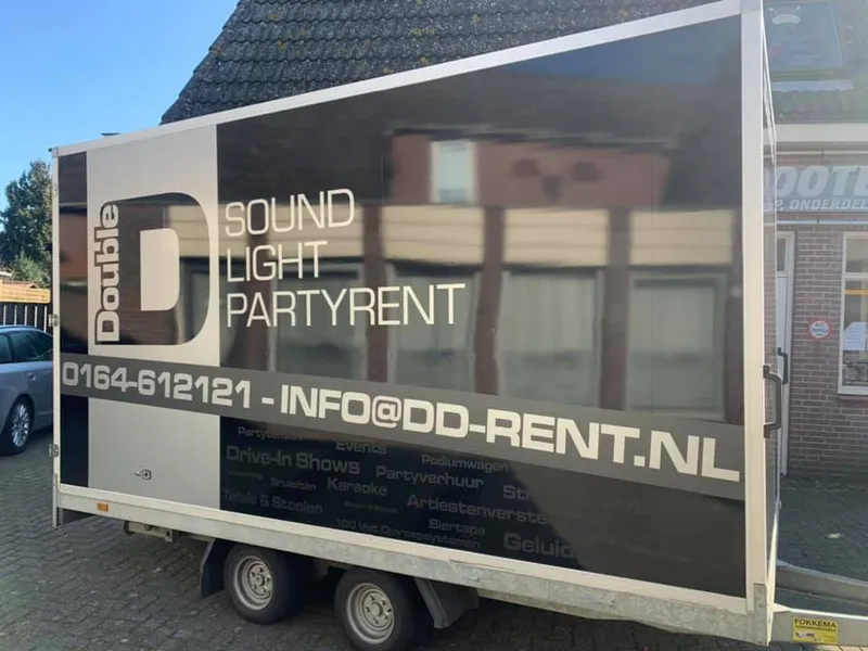 Gesloten aanhangwagen met zwarte en grijze belettering en contactgegevens