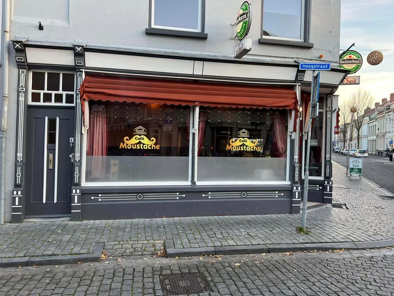 Cafépui met goudkleurige raamstickers met snorlogo op twee grote ramen